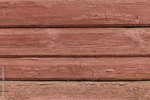 The old facade of the house is made of horizontal wooden boards. Peeling brown paint