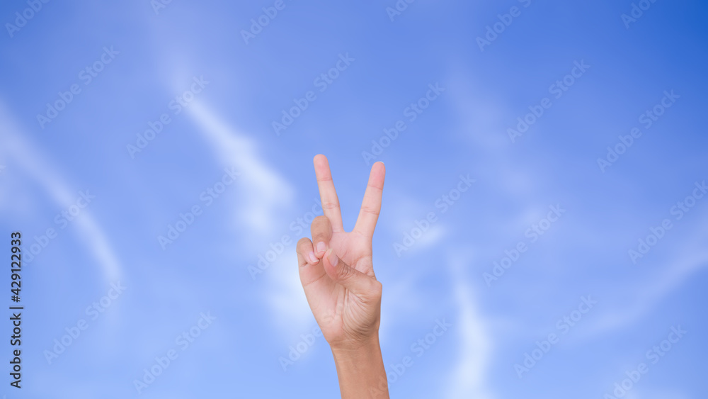 Slim hand woman two fingers showing isolated on blur image of blue sky. strength, new beginning, victory, encouragement, The fight, new hope, success symbols concept.