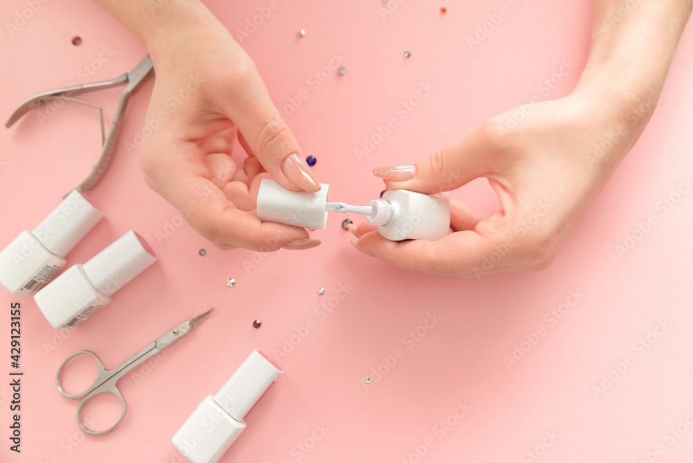 Woman making manicure herself, paints nails . Female hands with nail polish and manicure tools, on pink background, view from above. Nail care and beauty concept Woman making manicure herself, paints nails . Female hands with nail polish and manicure tools, on pink background, view from above. Nail care and beauty concept