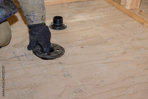 Plumber jointing installing sewage shower drain pipes on a house under construction