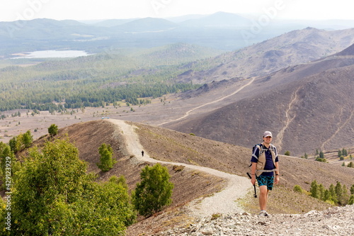 man and woman tourists stand on the top of Poklonnaya Gora against the background of Mount Karabash on a summer day. Chelyabinsk region. Russia photo