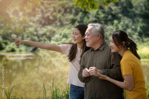 senior asian with family  enjoying good time , happy and smiling,outdoors family at nature park with beautiful sun flare.