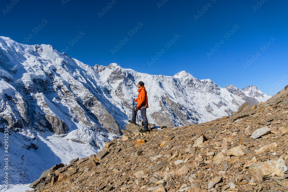 Beautiful landscape with mountains, blue huge glacier and a middle-aged mountaineer man against the background of mountains, glacier