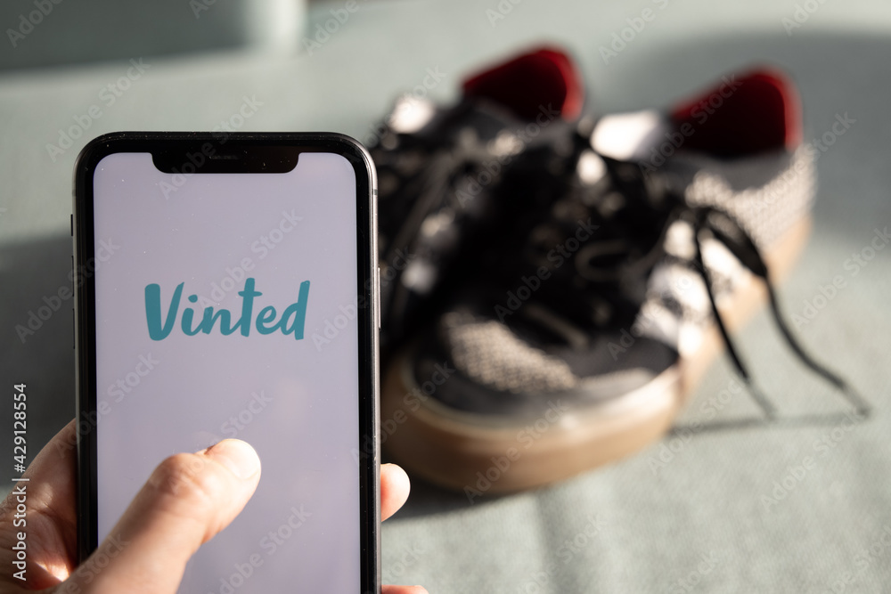 Iphone with vinted logo on screen with hand in front of style shoes. Vinted  is a Lithuanian online marketplace and community for second hand clothes,  accessories Stock Photo | Adobe Stock