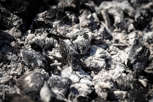 Black burnt coals in the grill close-up.