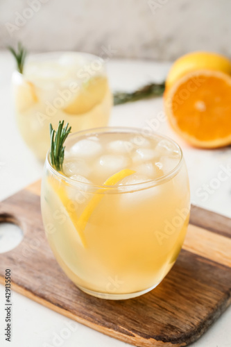 Glass of cold tea with rosemary and citrus fruits on light background