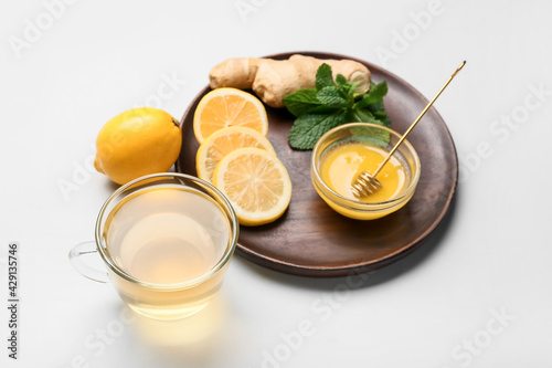 Cup of tea with ginger, honey and lemon on light background