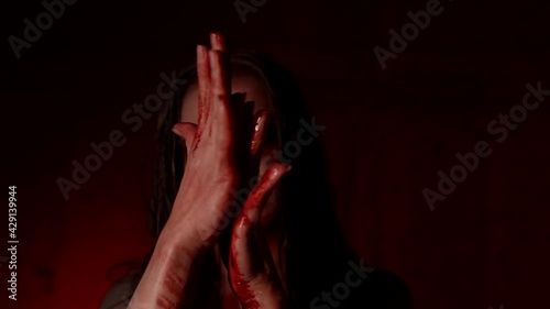 vampire woman with black eyes is licking blood from her arms, possessed by devil lady