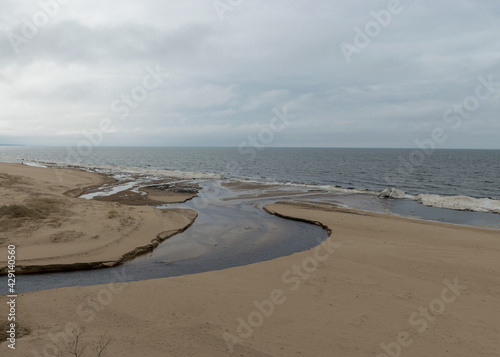 the river estuary to the sea, winter day, ice shapes on the sea shore, cloudy weather, blurred sky