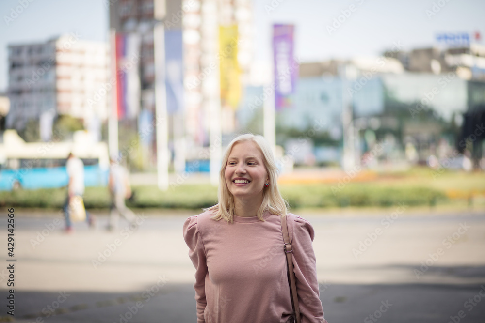 Portrait of smiling blond woman on the street.