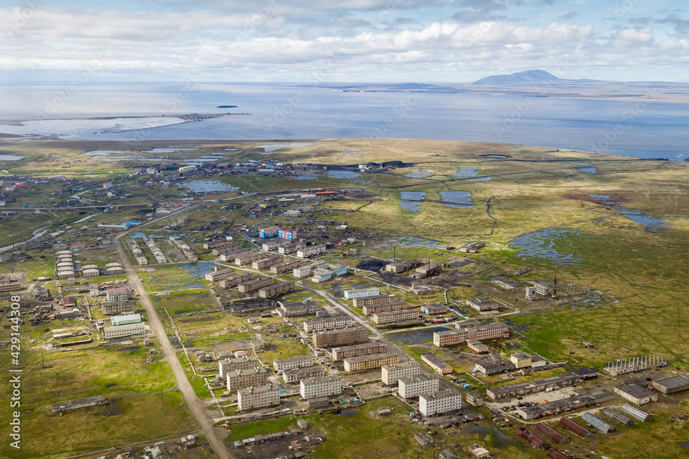 Summer aerial view of a northern settlement in the Arctic. Top view of the streets and buildings in the tundra. Anadyr estuary in the distance. Ugolnye Kopi, Chukotka, Siberia, Far East of Russia.