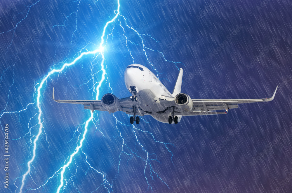 Fototapeta premium Lightning hits strike during a heavy downpour, behind a flying plane.