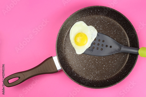 Fried egg in a frying pan on a pink background