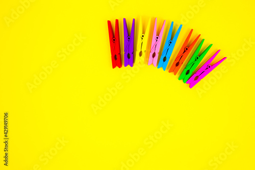 Colorful wooden clothespins on yellow background. Close up, copy space. Minimalism, original and creative photo. Be another. Individuality concept. Vertical Wallpaper for smartphone.