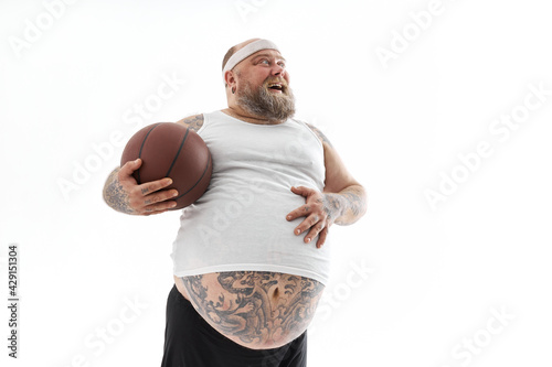 bearded fat caucasian tattoed man with basketball ball in white background. He is funny and happy © Yaroslav Astakhov