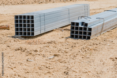 Hollow metal beams laying on sandy ground