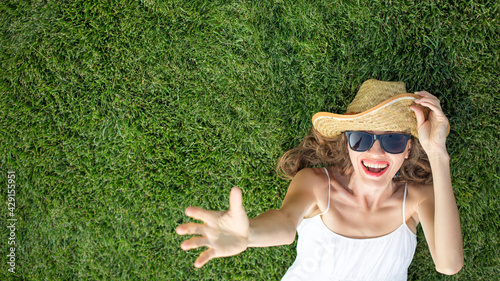 Woman wearing hat and sunglasses and lying on green grass, top view  © PEPPERSMINT