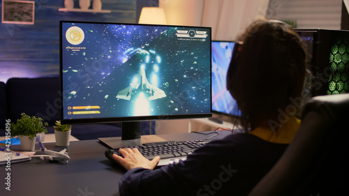 Player sitting on gaming chair and start playing space shooter video game wearing professional headset. Modern studio equipped with RGB system desktop, keyboard, mouse, using technology network