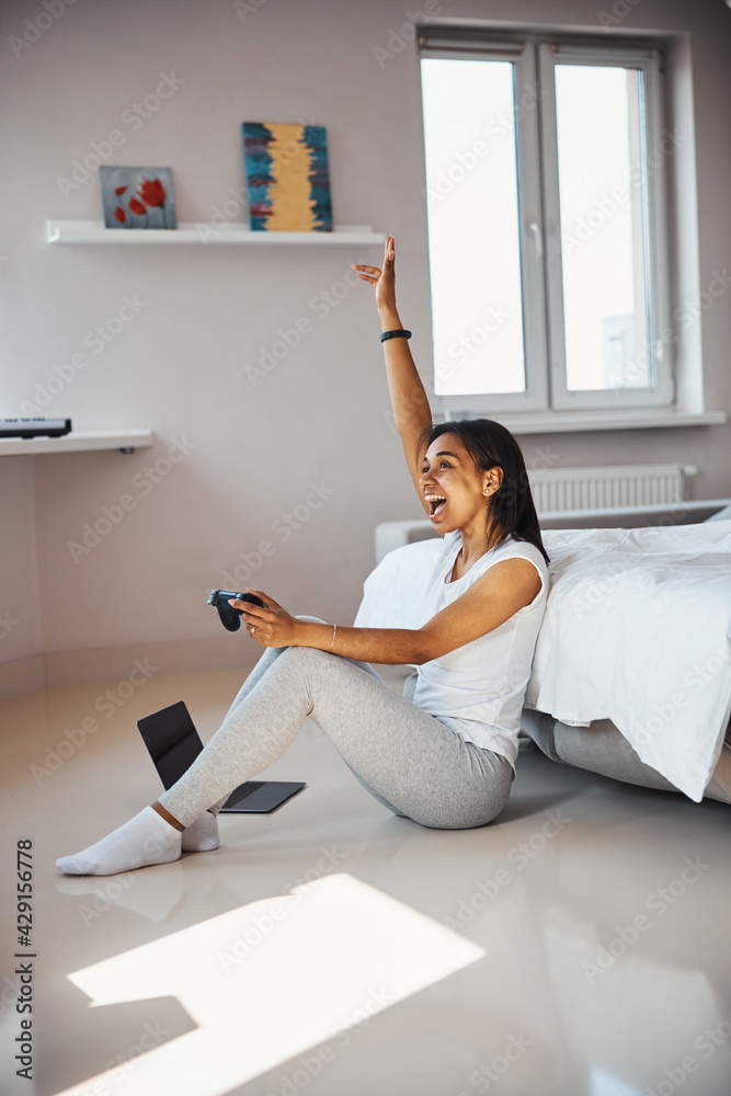 Cheerful young woman paying video game at home