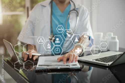 The doctor working on the table, examine the concept of finding information and documents in hospital room.