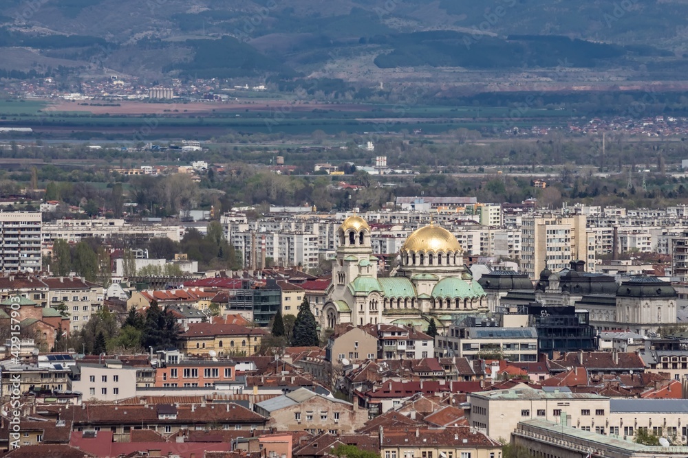 Aerial view of urban landscape with many administrative and residential buildings, shining golden domes of cathedral. Sofia, the capital city of Bulgaria, East Europe. Panoramic natural sight.