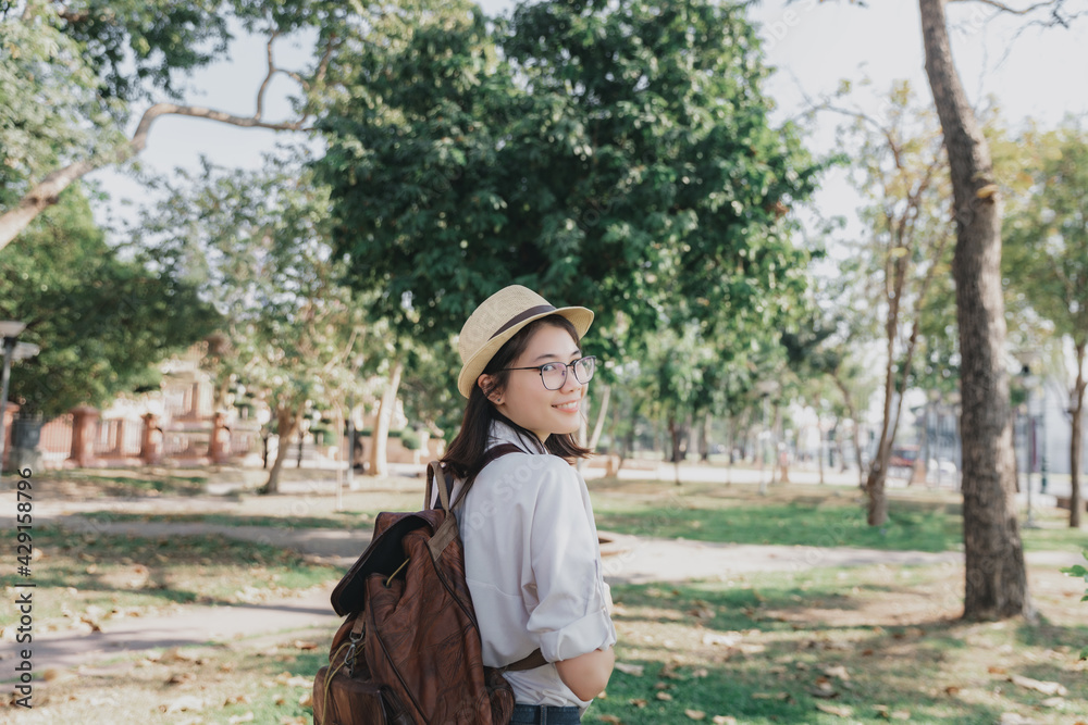 Obraz premium Young asian woman with backpack and straw hat walking in park