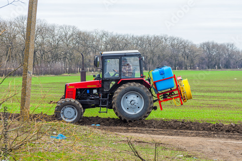 The tractor is preparing to spray and fertilize wheat crops. A tractor in a field with wheat. Tractor applies fertilizer.