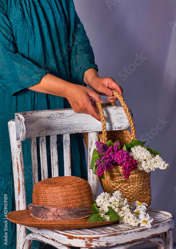 Woman holding hands wicker bag with lilac flowers indoor photo