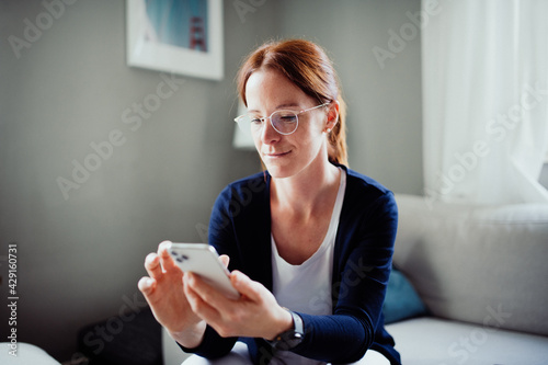 Frau Zuhause im Wohnzimmer mit Smartphone