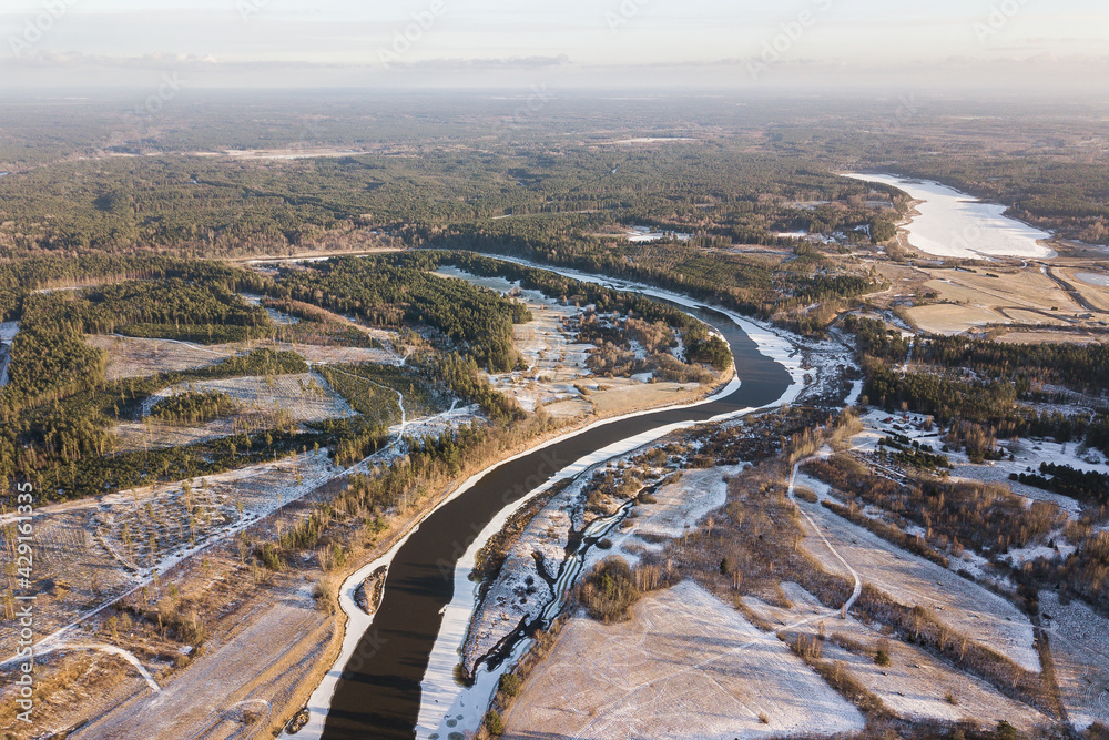 Aerial view of river bend and forests on a sunny winter day. 