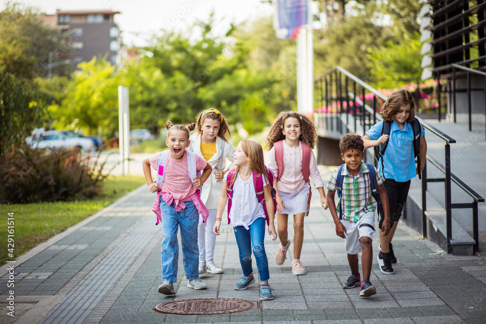 Obraz premium School kids going to school together. Focus is on background.