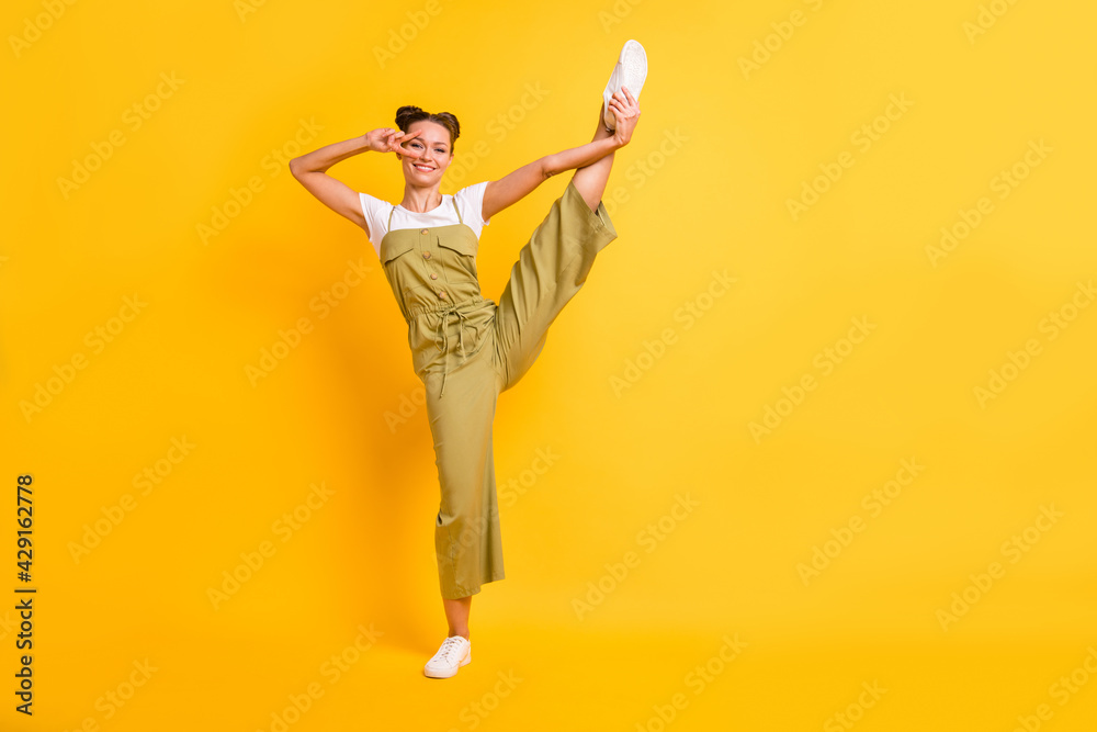 Full length body size view of pretty cheerful girl dancing having funs balance howing v-sign isolated over bright yellow color background Full length body size view of pretty cheerful girl dancing having funs balance howing v-sign isolated over bright yellow color background