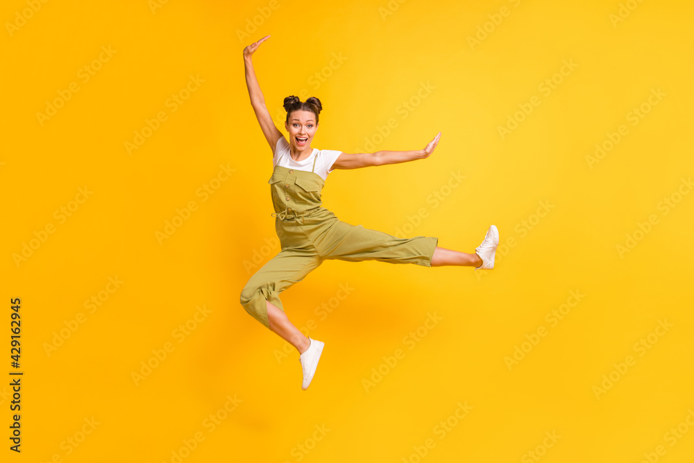 Photo of excited funny fighter lady jump kick leg wear green overall footwear isolated yellow background