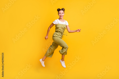 Full length body size view of charming cheerful girl jumping running having fun isolated over bright yellow color background