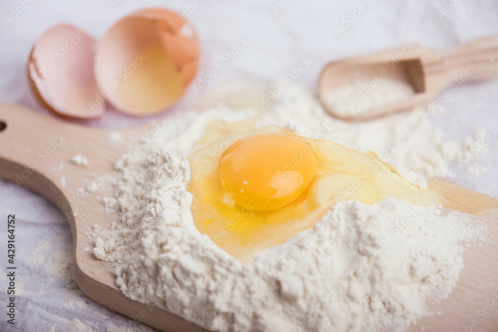 Flour and egg yolk on wooden cutting board Flour and egg yolk on wooden cutting board