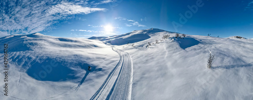 Cross country skiing slope running though stunning snow covered mountain terrain on a cold sunny winters day,.