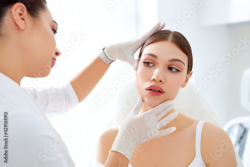 Cosmetologist in gloves checking face of woman