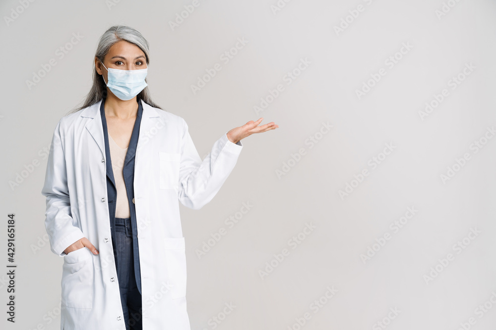 Asian mature woman in protective mask gesturing at copyspace Asian mature woman in protective mask gesturing at copyspace