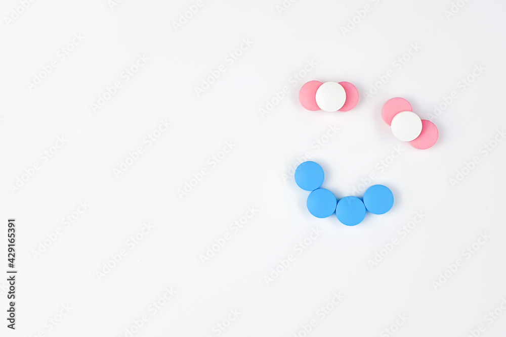 Smiling face sign made of vitamins. Vitamins and supplements isolated on white background. Concept for a healthy dietary supplementation. Close up. Copy space.