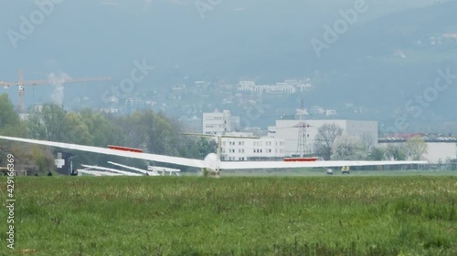 Small white glider landing on runway. Flying gliders as hobby, graceful and expensive small private airplane.. Heat wave distortion on runway. 