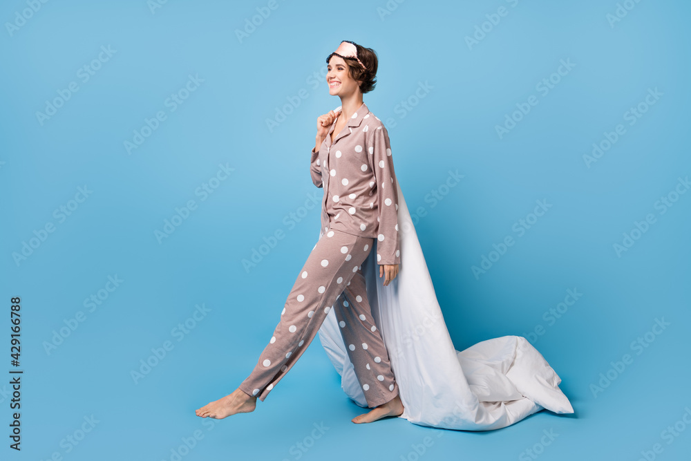 Full length profile side photo of young excited girl happy positive smile go sleep hold duvet isolated over blue color background Full length profile side photo of young excited girl happy positive smile go sleep hold duvet isolated over blue color background