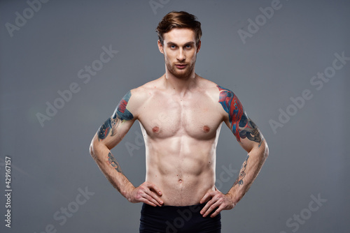 sporty man pumped up press acting out on his arms cropped view gray background