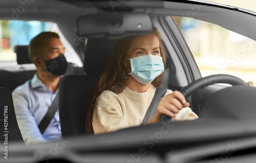 transportation, health and people concept - female driver driving car with male passenger wearing face protective medical mask for protection from virus disease © Syda Productions
