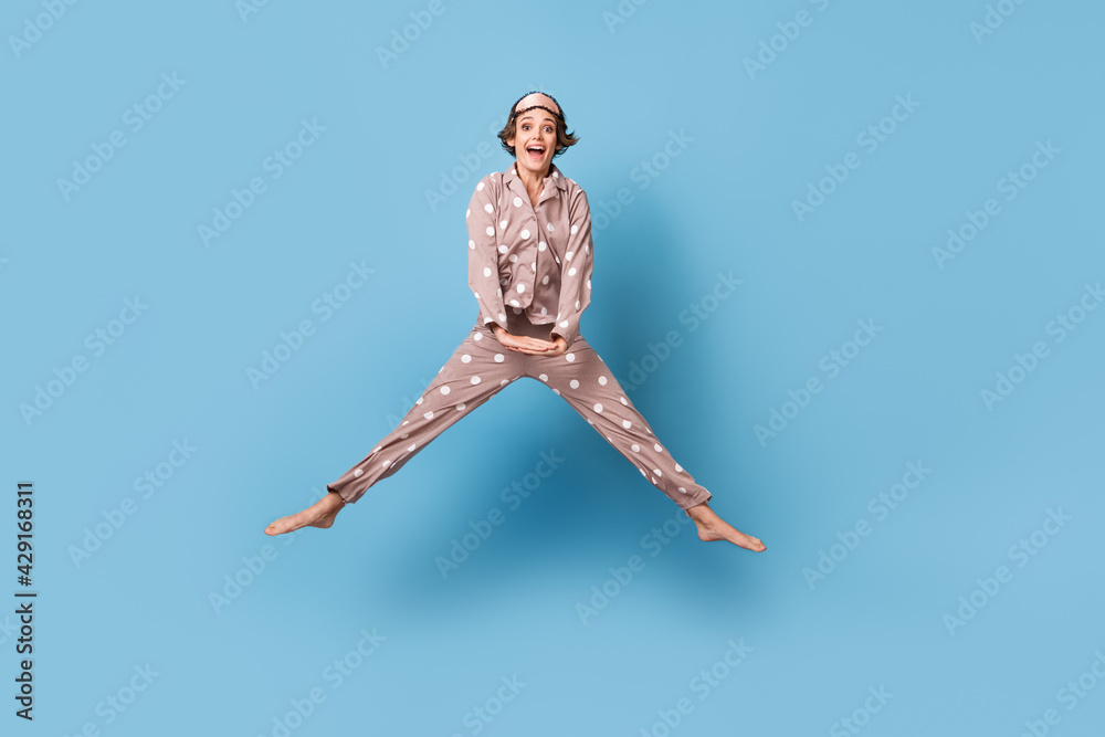 Full size photo of young pretty charming happy smiling girl in pajamas jumping isolated on blue color background Full size photo of young pretty charming happy smiling girl in pajamas jumping isolated on blue color background