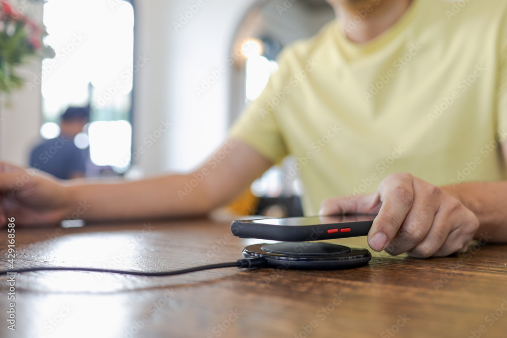 Charging mobile phone battery with wireless device in the table. Smartphone charging on a charging pad. Mobile phone near wireless charger. Charging mobile phone battery with wireless device in the table. Smartphone charging on a charging pad. Mobile phone near wireless charger.