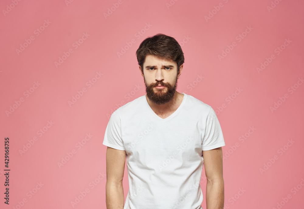 Man on a pink background in a white t-shirt emotions model cropped view Man on a pink background in a white t-shirt emotions model cropped view
