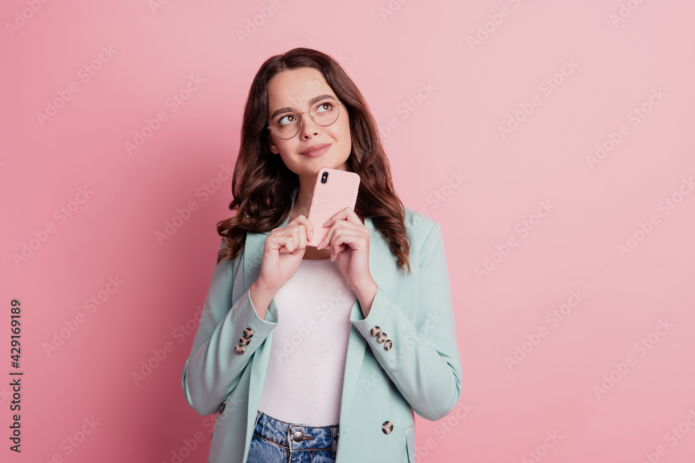 Close up photo of attractive smiling girl hold smartphone dreamy look up empty space chatting Close up photo of attractive smiling girl hold smartphone dreamy look up empty space chatting