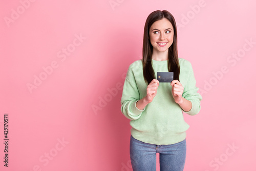 Photo of optimistic sweet brunette girl show card look empty space wear lime shirt jeans isolated on pink color background