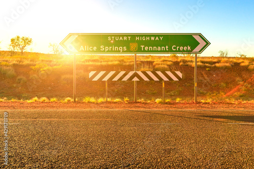 Northern Territory, Australia Outback. Stuart Highway signboard direction Alice Springs or Tennant Creek. Tourism in Central Australia, Red Centre. Sun with rays at sunset. photo