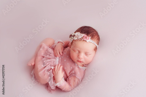 Lovely newborn girl sleeping on pink blanket  . Closeup portrait of a beautiful,  sleeping baby girl. Newborn asleep on a blanket. motherhood, childbirth concept
